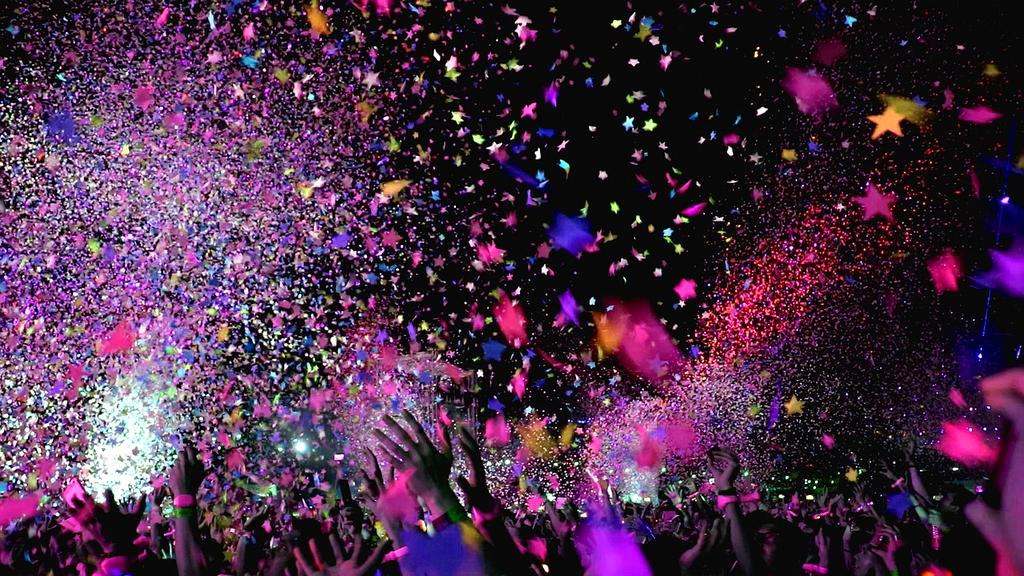 Energetic concert crowd with raised hands and stage lights