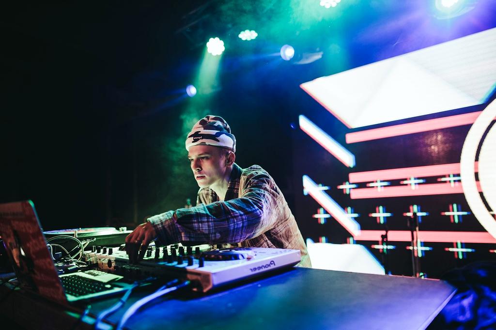 DJ performing with colorful laser lights and smoke effects at electronic music venue